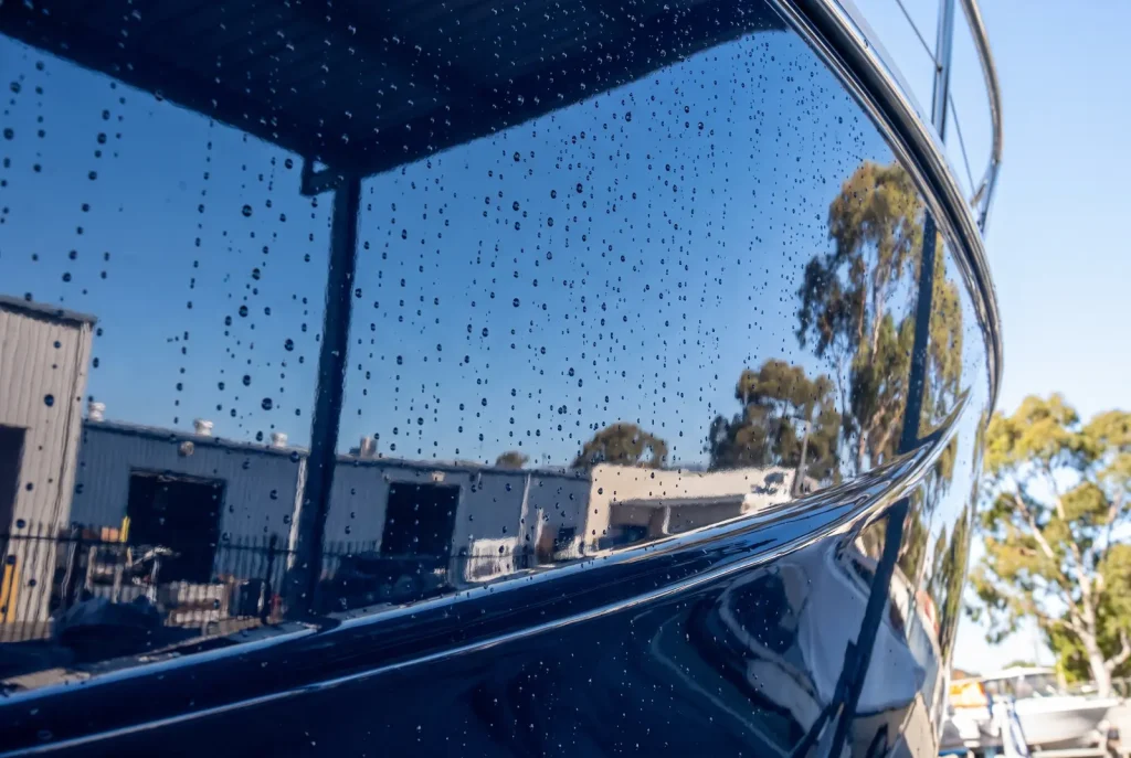 Close-up of mirror-polished navy boat hull gelcoat detailed by Shipshape Boat Detailing in O'Connor WA